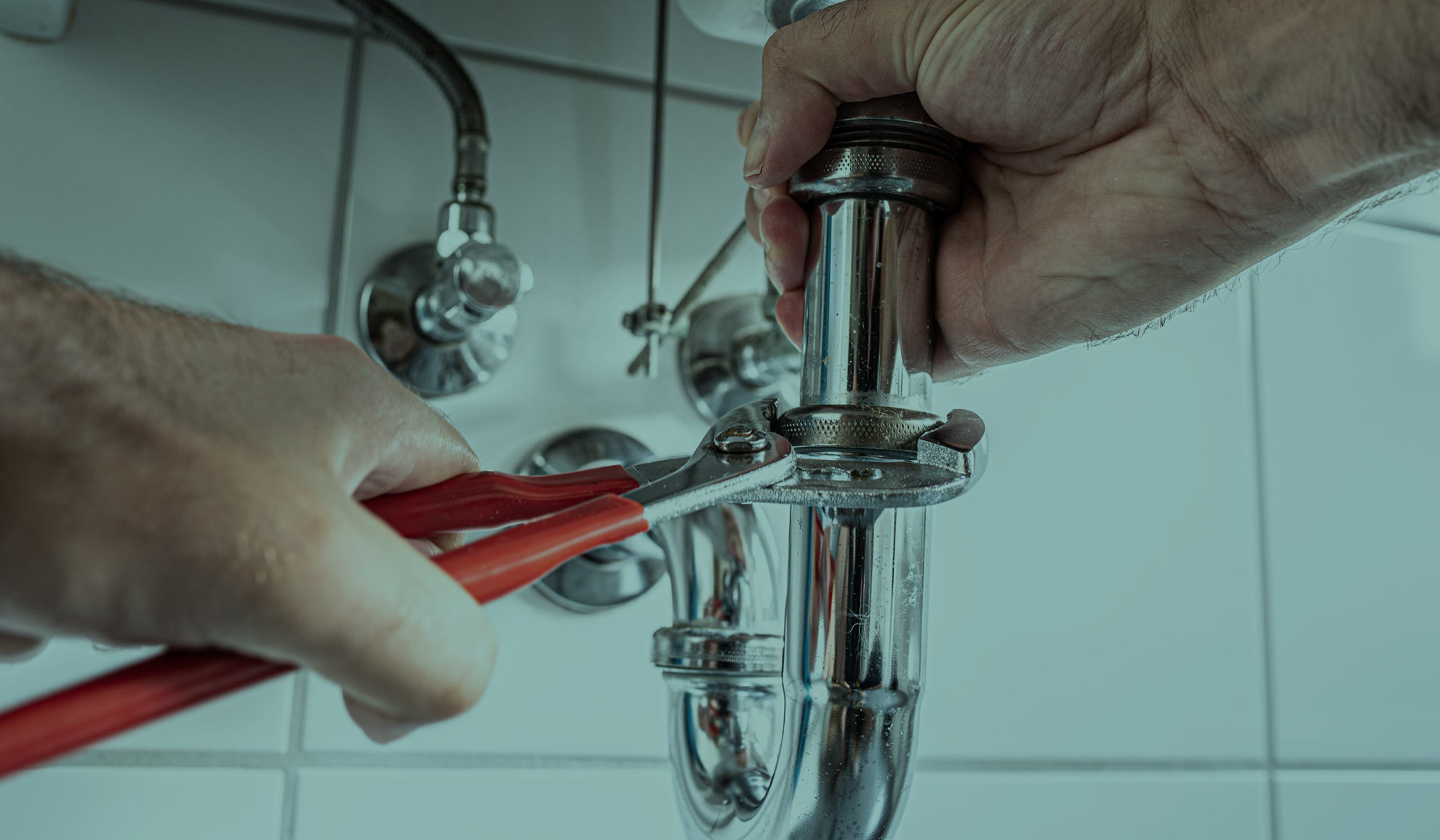 plumber with wrench repairing bathroom sink pipes Dallas TX